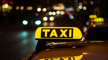 segno-giallo-e-nero-di-taxi-posto-sopra-un-auto-di-notte