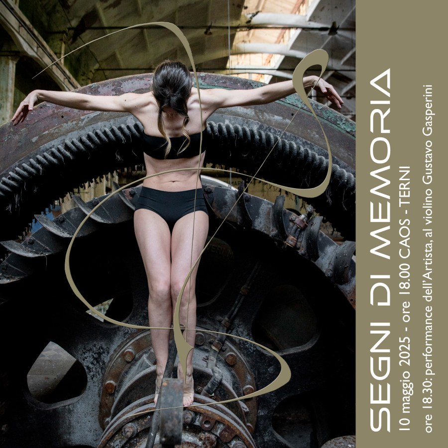 Un'artista performativa in posa su un grande ingranaggio industriale, parte dell'installazione 'Segni di Memoria'.