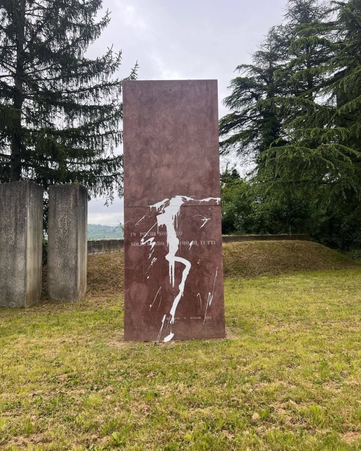 Monumento dedicato al partigiano Aldo Bologni, vandalizzato, con un'immagine della superficie danneggiata in un contesto naturale.