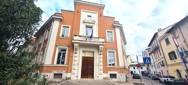 Facciata dell'Istituto d'Arte 'Metelli' a Terni, con ingresso principale e bandiere italiane, circondata da vegetazione e segnaletica stradale.