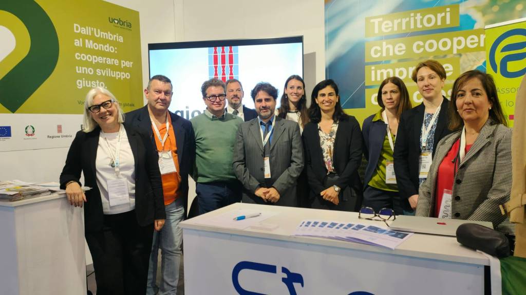 Un gruppo di professionisti e rappresentanti delle associazioni e imprese umbre pose davanti allo stand della Regione Umbria durante Codeway Expo, un evento dedicato alla cooperazione internazionale.