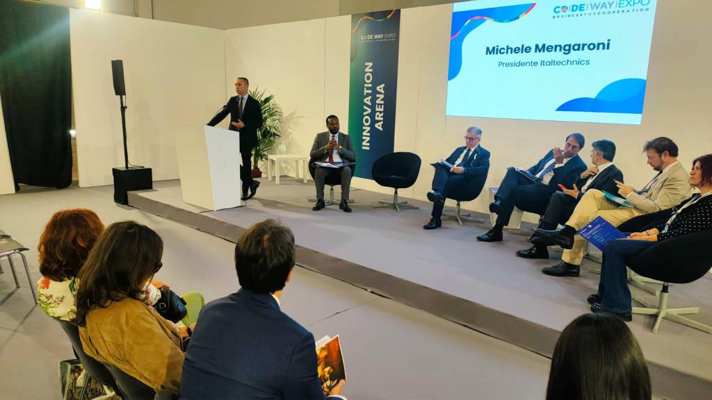 Un panel di discussione durante l'evento Codeway Expo, con relatori e pubblico in un'area dedicata all'innovazione. Sul palco, un uomo parla a un podio mentre altri partecipanti siedono in fila, attentamente ascoltando.