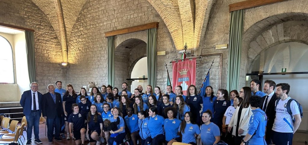 Ragazze della Nazionale femminile U20 di rugby in posa con il personale e i rappresentanti locali in una sala del Comune di Gubbio.