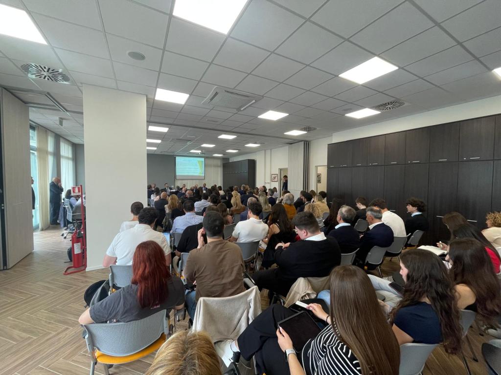 Una sala affollata durante un convegno giuridico sulla circolazione dei beni immobili, con relatori e partecipanti seduti e un proiettore visibile sullo sfondo.