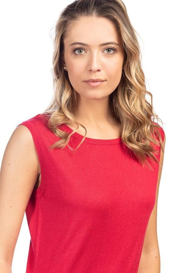 Ritratto di una giovane donna con capelli ondulati e castani, indossante una maglietta rossa semplice, che guarda direttamente in camera con un'espressione neutra.