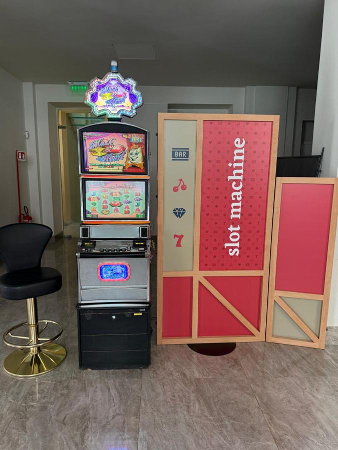 A slot machine displayed in a bright area, with colorful screens showing various symbols. Next to the machine is a decorative partition with the words 'slot machine' and a bar symbol.