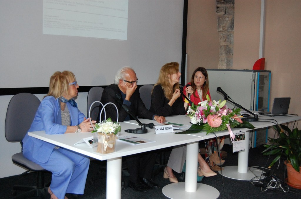 Un evento di chiusura dell'anno accademico 2024-2025 dell'Università della Terza Età di Terni, con Laura Guercio che parla a un tavolo di relatori, decorato con fiori e materiale informativo.