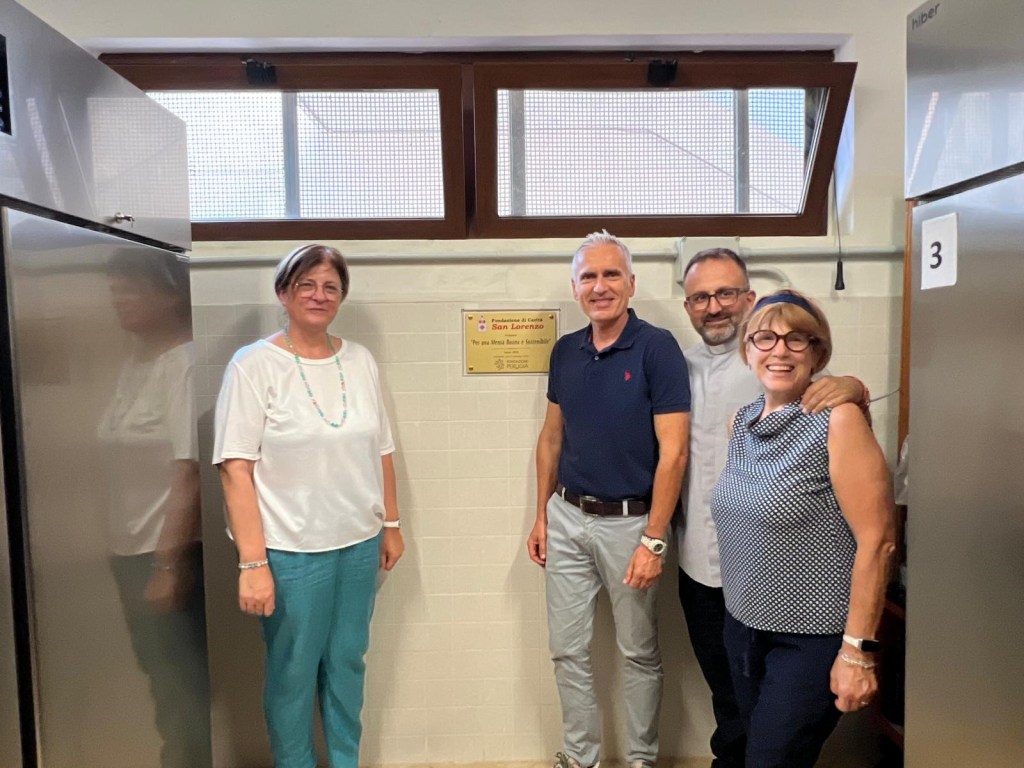 Inaugurazione di nuovi armadi refrigerati presso la Mensa Caritas 'Don Gualtiero', con quattro persone presenti, in un ambiente luminoso.