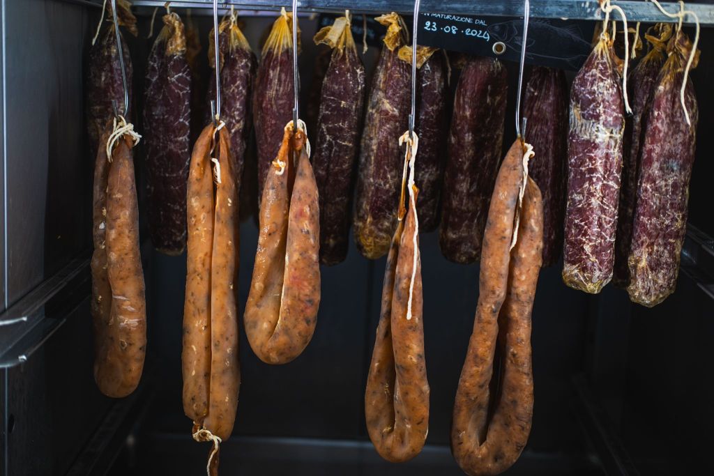 Un assortimento di salumi a base di pesce appesi, con mortadelle di mare e salami di mare in esposizione nelle vetrine di una pescheria.