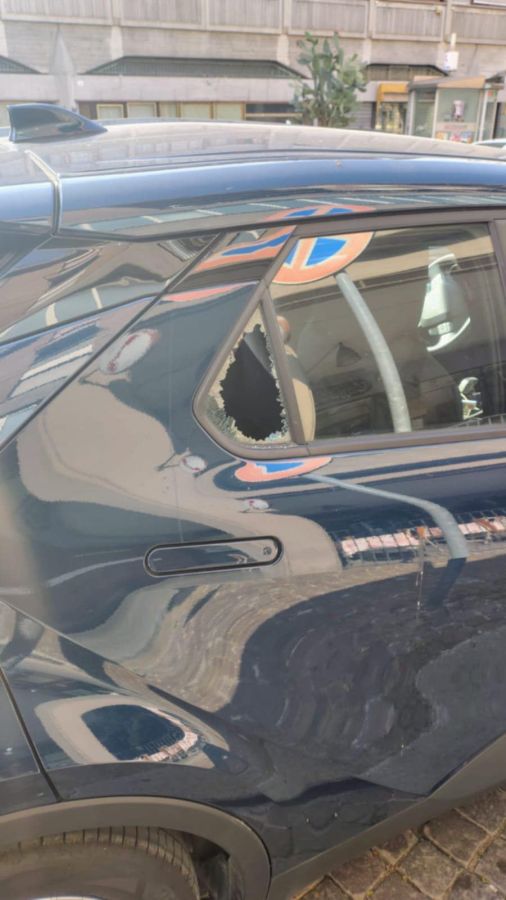 Auto parcheggiata con finestrino rotto e vetri sul suolo, evidenziando danni da tentato furto.