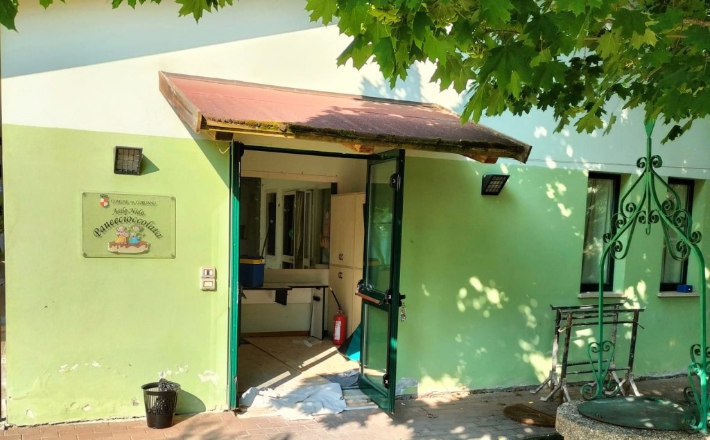 Entrata principale dell'asilo nido 'Pane e Cioccolata' a Chiugiana, con alcuni lavori di ristrutturazione in corso, visibile un'estintore e materiali di costruzione all'interno.