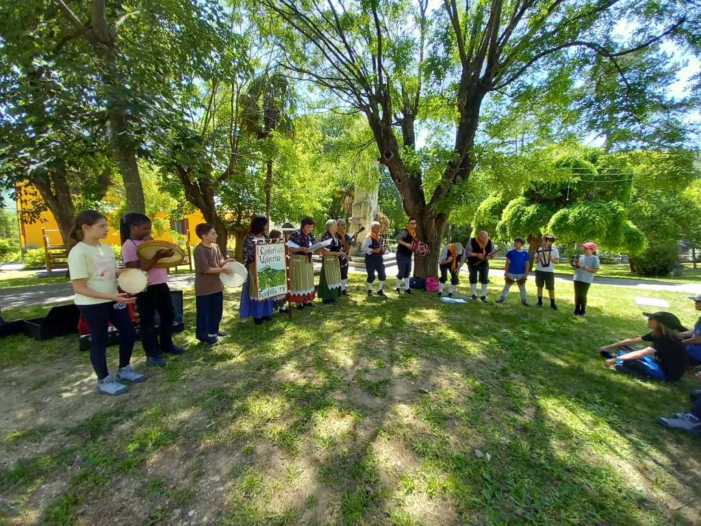 Gruppo di bambini e adulti che suonano strumenti musicali all'aperto, circondati da alberi e verde nel parco.