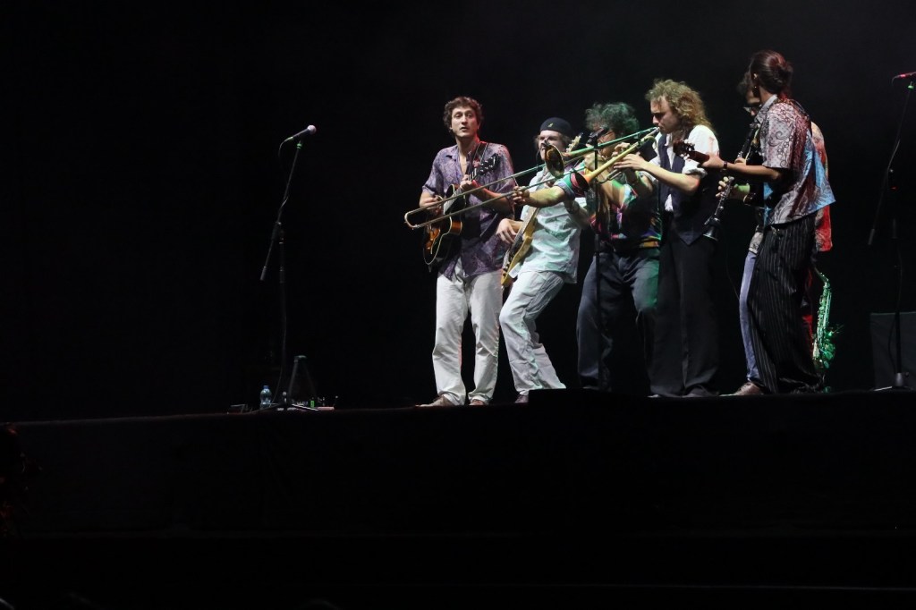 A group of musicians performing on stage, playing various instruments during a live concert.
