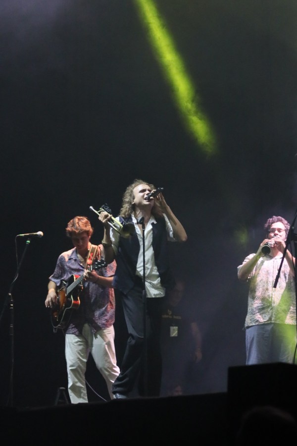 Band performing live on stage with microphones and instruments, illuminated by colorful stage lights.