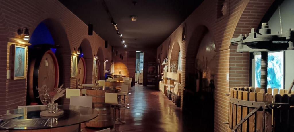 Interno della cantina Dionigi a Bevagna, con un corridoio illuminato che presenta botti in legno, tavoli e opere d'arte appese alle pareti.