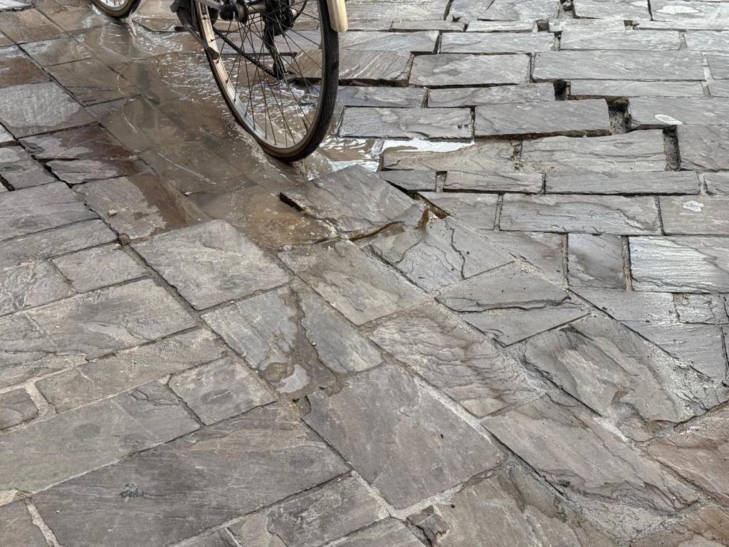 Un'immagine che mostra una bicicletta su una pavimentazione irregolare e bagnata, evidenziando lo stato di degrado e le difficoltà nel centro di Terni.