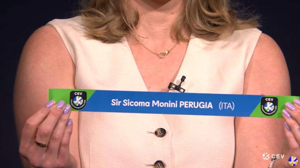 Un'immagine di una persona che mostra un cartello con la scritta 'Sir Sicoma Monini PERUGIA (ITA)' e logo del CEV.