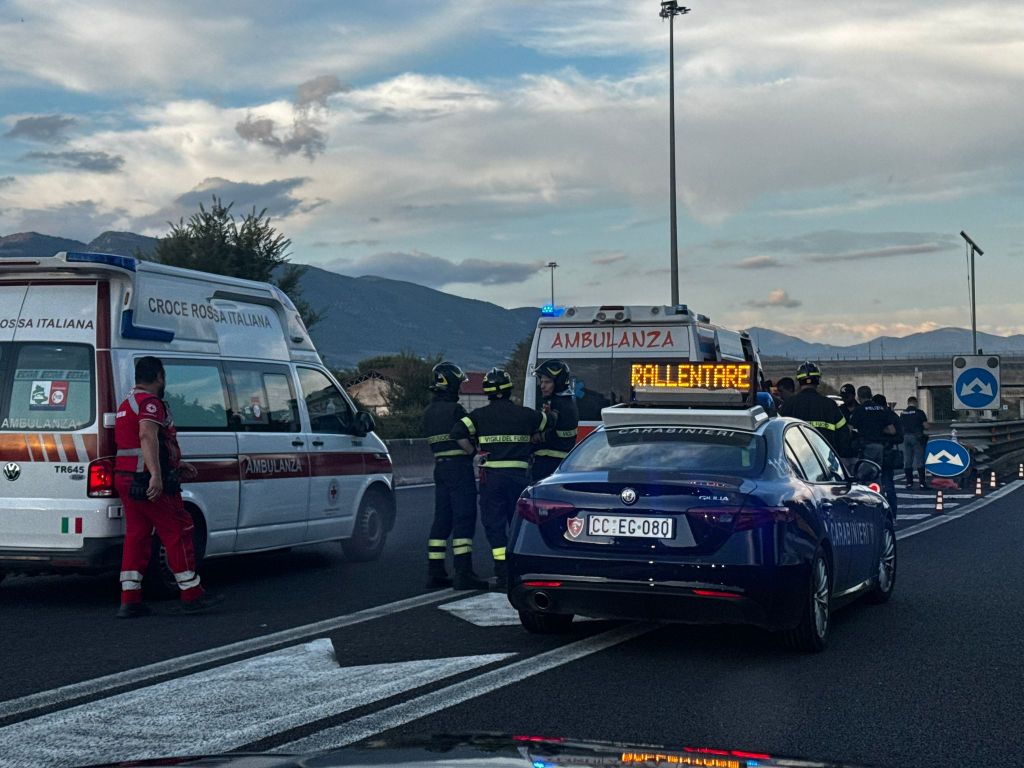 Emergency responders at the scene of an incident, featuring an ambulance and a police car with flashing lights on a roadway.