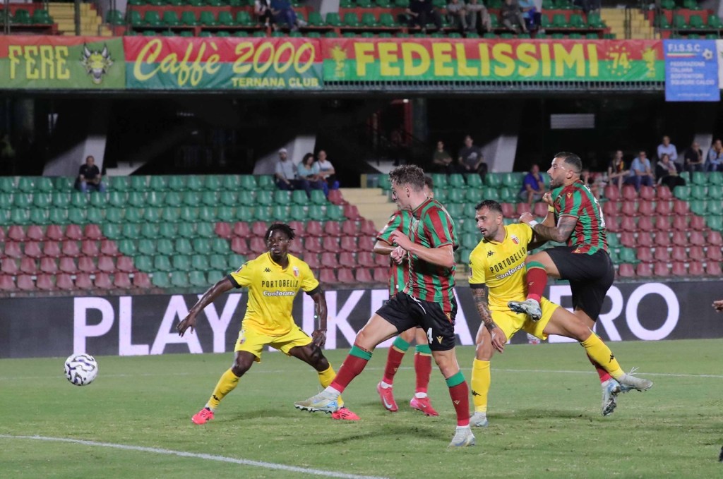 A dynamic moment from a soccer match featuring players in yellow and green striped jerseys competing for the ball on a grassy field.