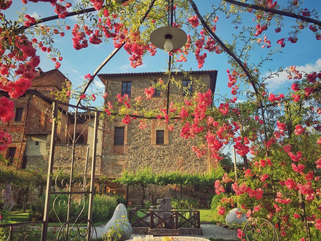 Giardino fiorito con rosa rampicante e vista su un edificio in pietra antique.