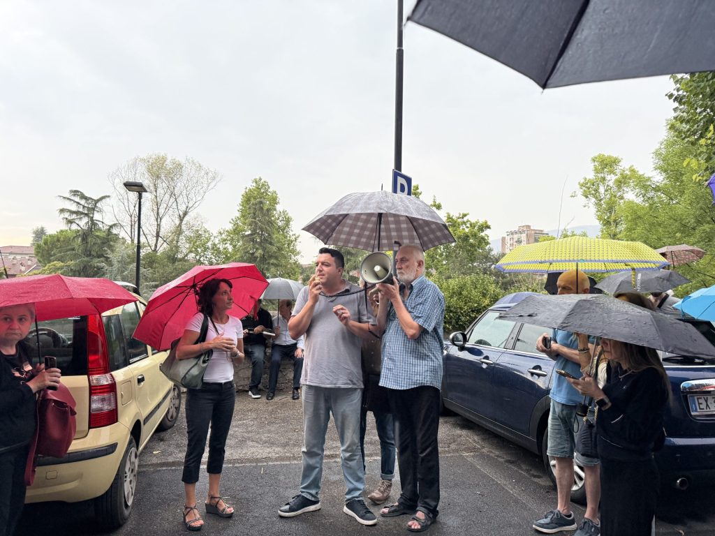 Un gruppo di manifestanti sotto la pioggia, alcuni con ombrelli, si riunisce per protestare contro il taglio di alberi a Terni.