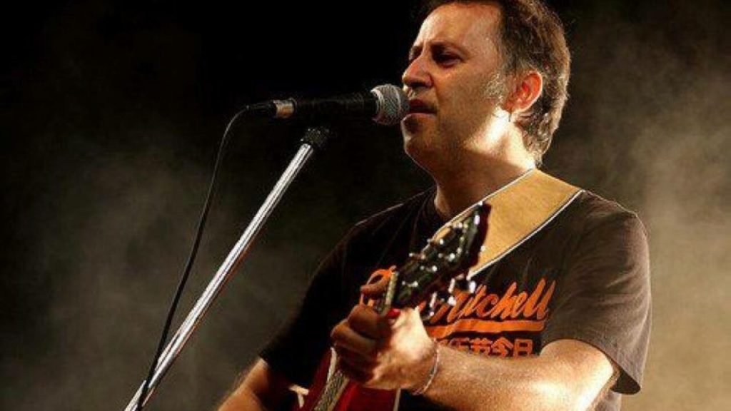 Un musicista al microfono mentre suona la chitarra in un'atmosfera di concerto.