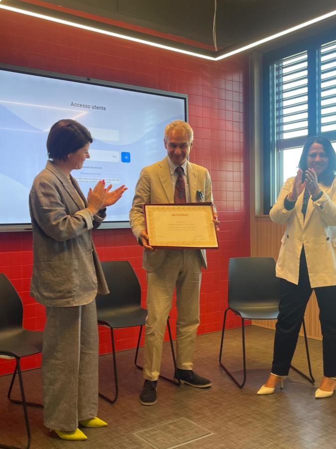 Cerimonia di premiazione di Stefano Cenni per i 40 anni di carriera, con Teresa Votta e Carlo Turchetta che applaudono.