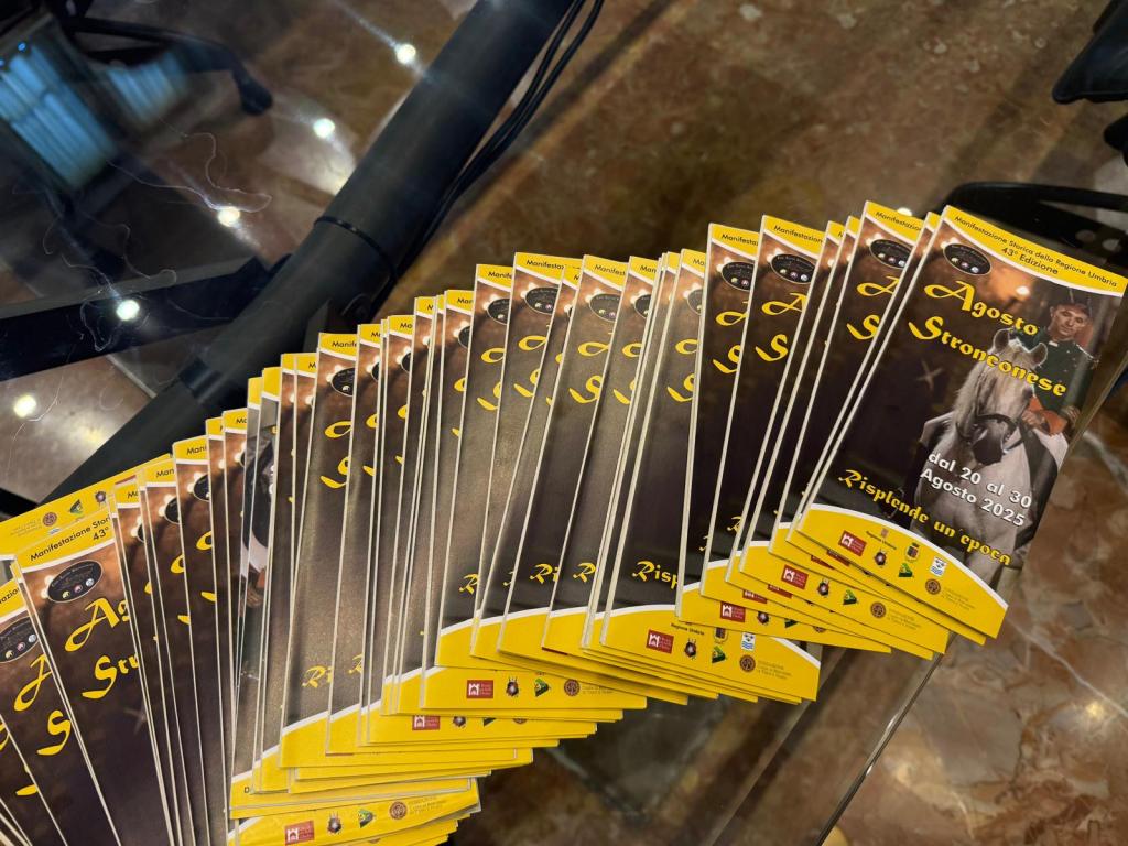 Un gruppo di volantini dell'Agosto Stronconese disposti su un tavolo, con dettagli sulla 43esima edizione dell'evento e immagini di cavalieri.