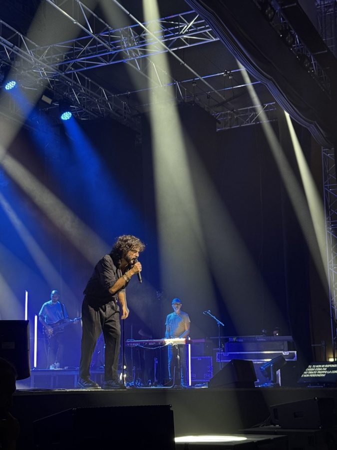 Francesco Renga performs on stage at the PalaTerni concert, surrounded by dramatic lighting and accompanied by band members.