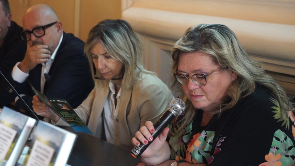 Un gruppo di relatori, inclusa una donna che parla in un microfono, durante un convegno sulla promozione dei cammini in Umbria.