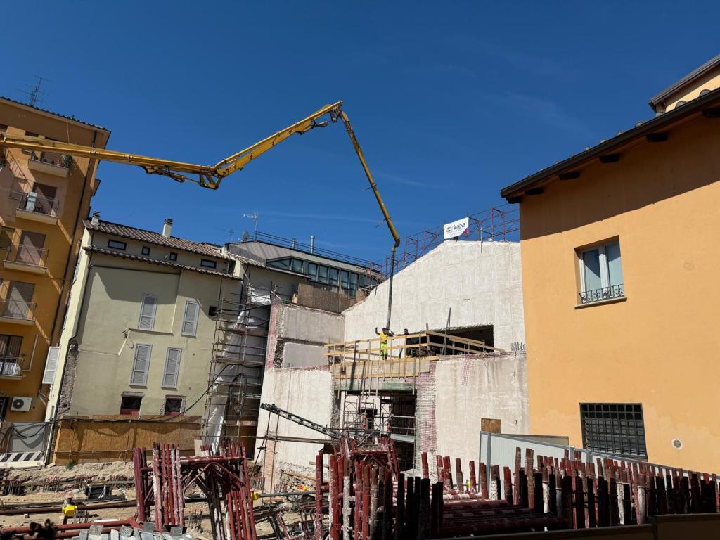 Cantiere edile a Ponte Romano con gru in azione e strutture in costruzione, sotto un cielo sereno.