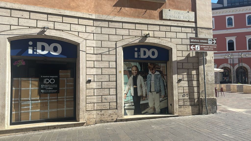 Insegna del negozio iDO con vetrina chiusa e scatole all'interno, in corso Cornelio Tacito.
