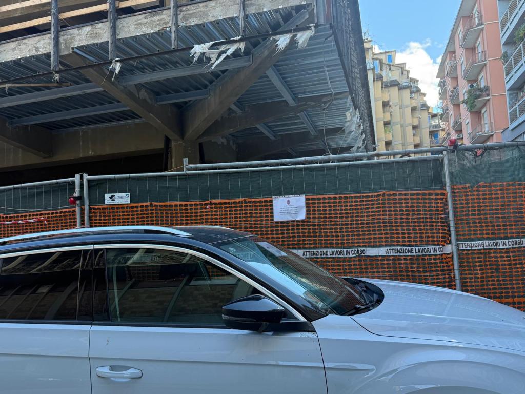 A white SUV parked in front of a construction site in Terni, Italy, with scaffolding and construction barriers visible.