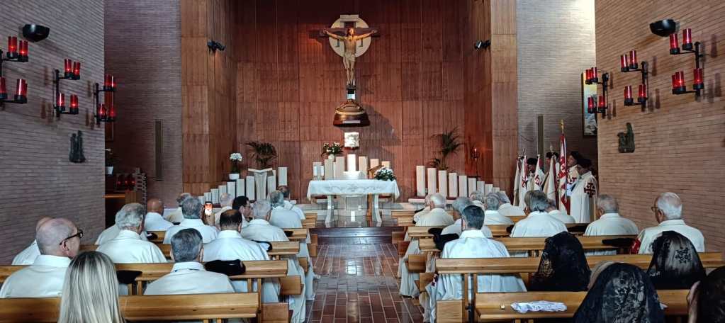 Interno del Santuario dell'Amore Misericordioso a Collevalenza durante la XXIII Giornata per la Terra Santa, con una vista dell'altare, crocifisso e partecipanti in abiti religiosi.