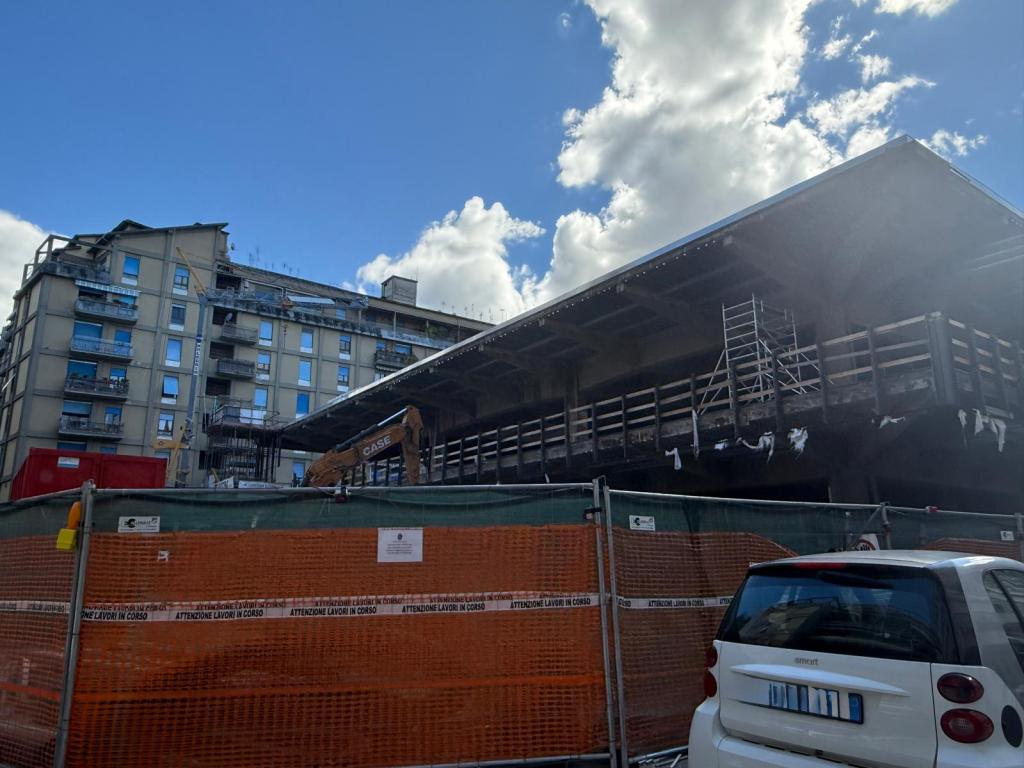 Construction site in Terni with a partially built structure and nearby residential building under a blue sky.