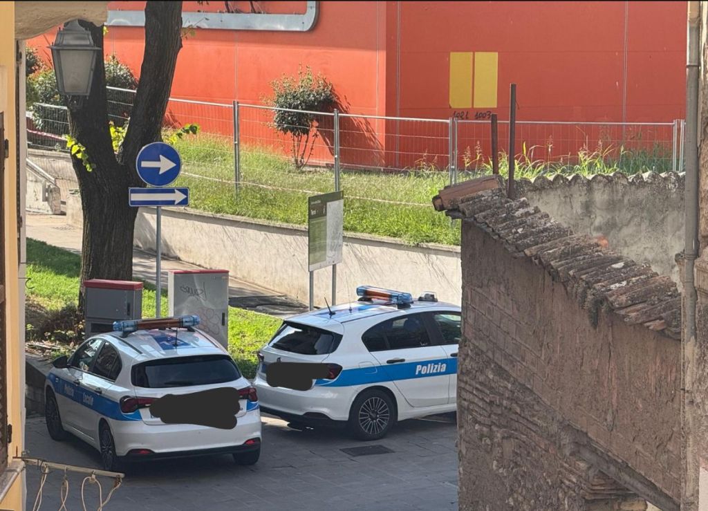 Due auto della polizia parcheggiate in un'area con segnaletica stradale, vicino a un cantiere del Teatro Verdi a Terni.