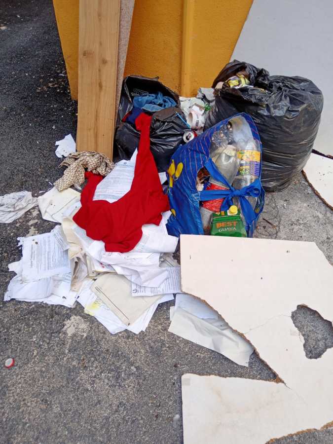 Accumulate di rifiuti e materiali vari abbandonati in un'area degradata vicino al Teatro Verdi, con sacchi neri e documentazione cartacea sparsa.