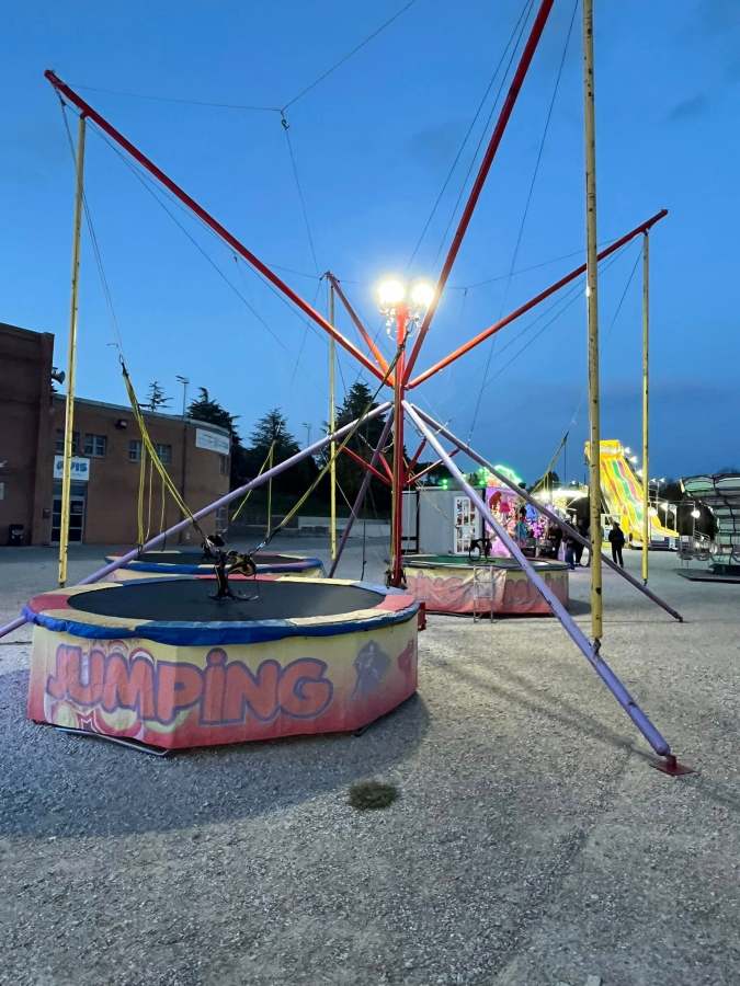 Struttura di giostre al luna park con un'attrazione chiamata 'Jumping', circondata da luci e altri giochi, in un ambiente allestito per il divertimento.