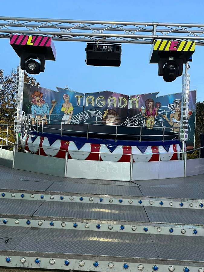 Vista della giostra Tagadà nel luna park al centro fiere di Montecastrilli, con decorazioni colorate e personaggi illustrati sullo sfondo.