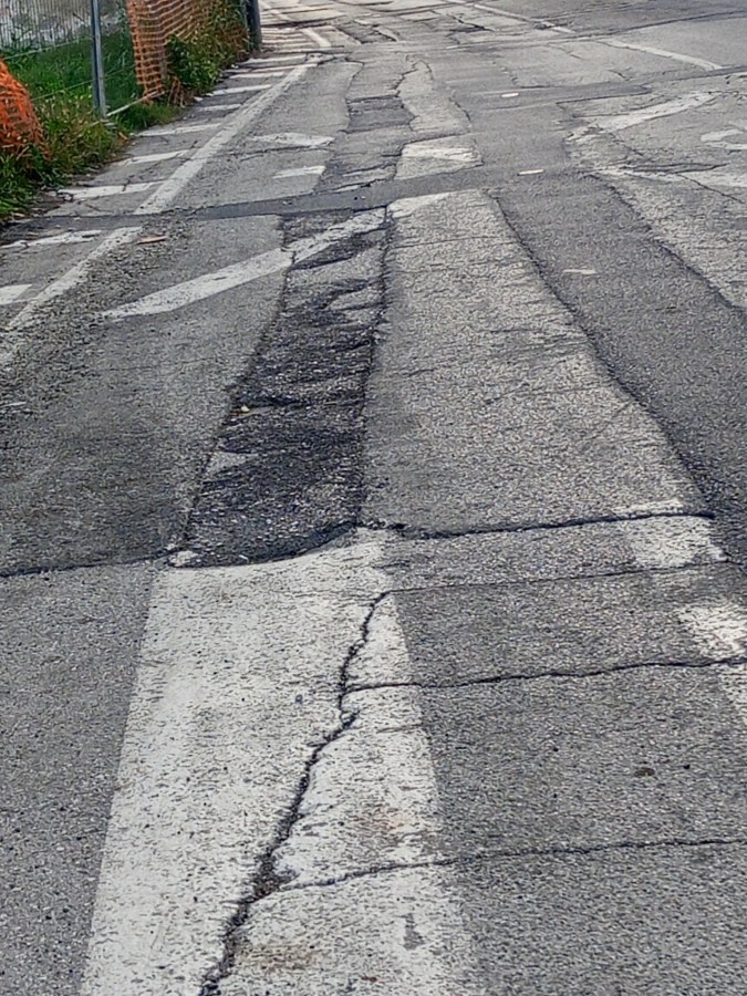 Uneven and cracked asphalt road with faded lane markings.