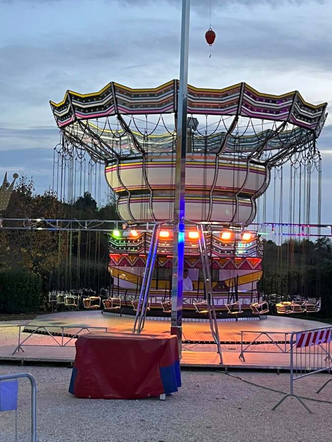 Giostra a catene illuminata allestita per un luna park, con sedie sospese e luci colorate.