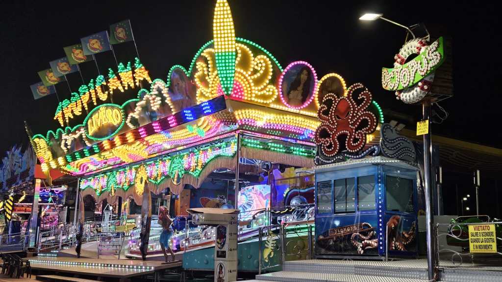 Luna park at night featuring a colorful ride with bright lights and an octopus design.