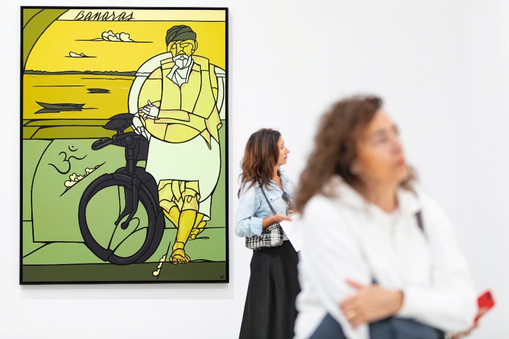 Un'opera di Valerio Adami esposta in una galleria, raffigurante un uomo seduto accanto a una bicicletta, con toni gialli e verdi. Due visitatori ammirano l'opera.