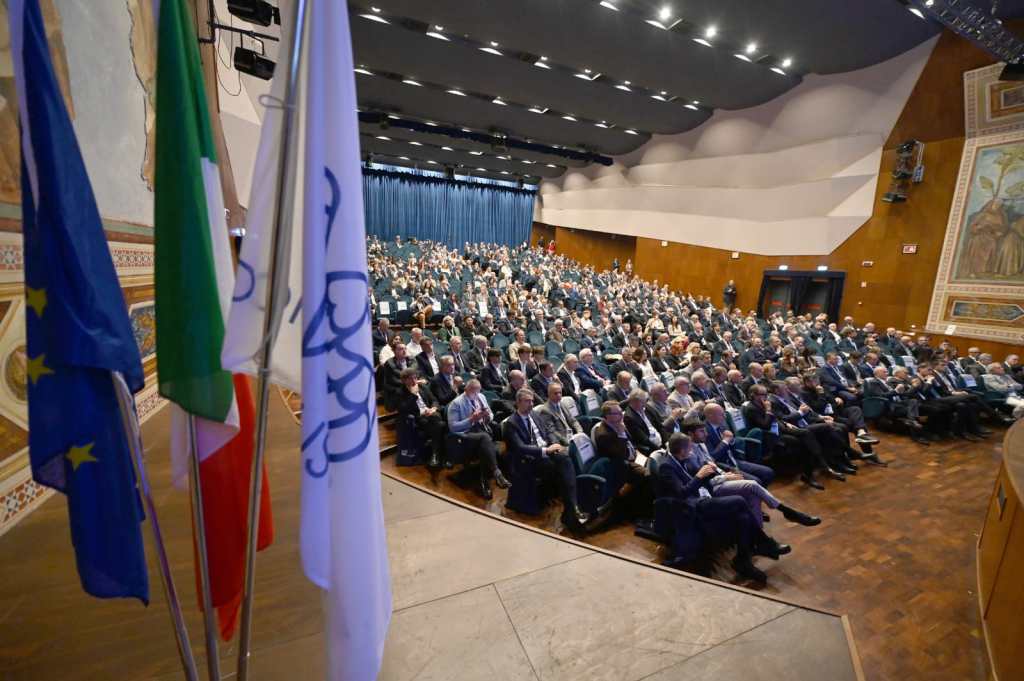Partecipanti all'Assemblea Generale di Confindustria Umbria al Teatro Lyrick di Assisi, con pubblico in sala e bandiere visibili.