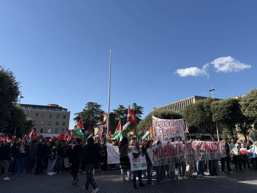 Una folla di manifestanti con bandiere palestinesi e striscioni in una piazza a Terni durante una protesta per sostenere la Palestina.