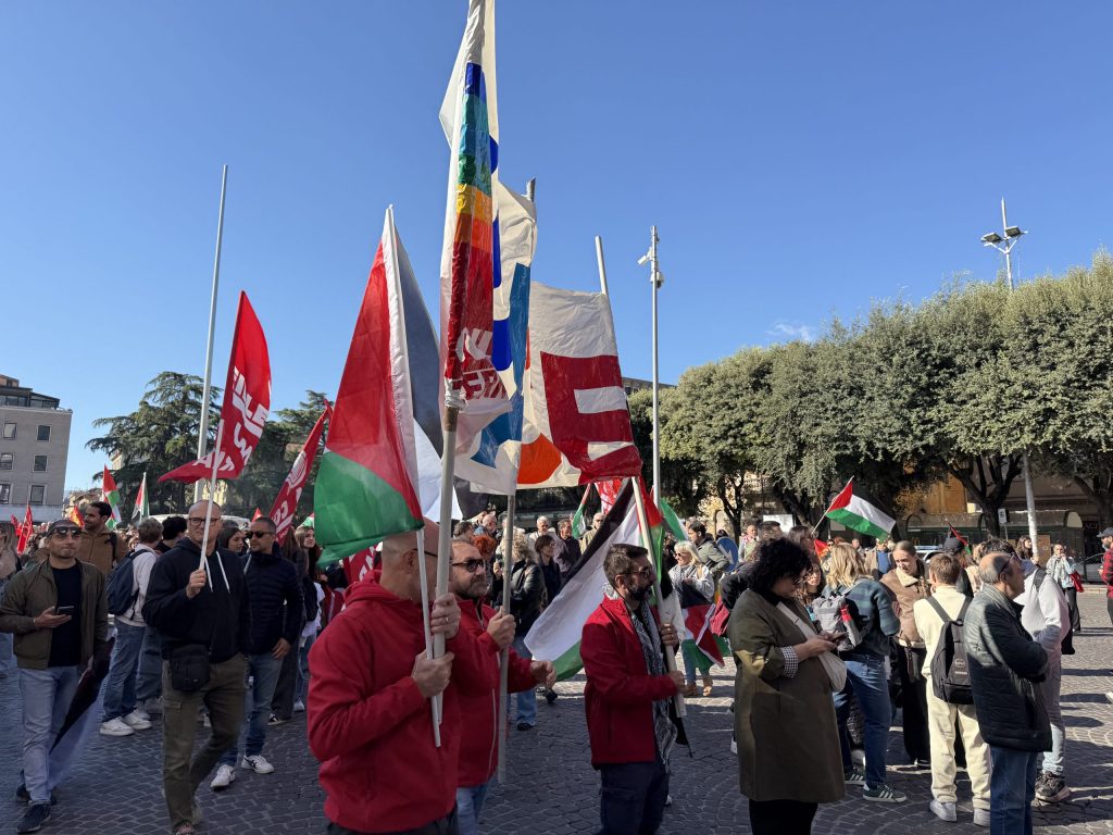 Manifestazione a Terni con partecipanti che sventolano bandiere palestinesi e altri stendardi, mentre si radunano in segno di protesta.
