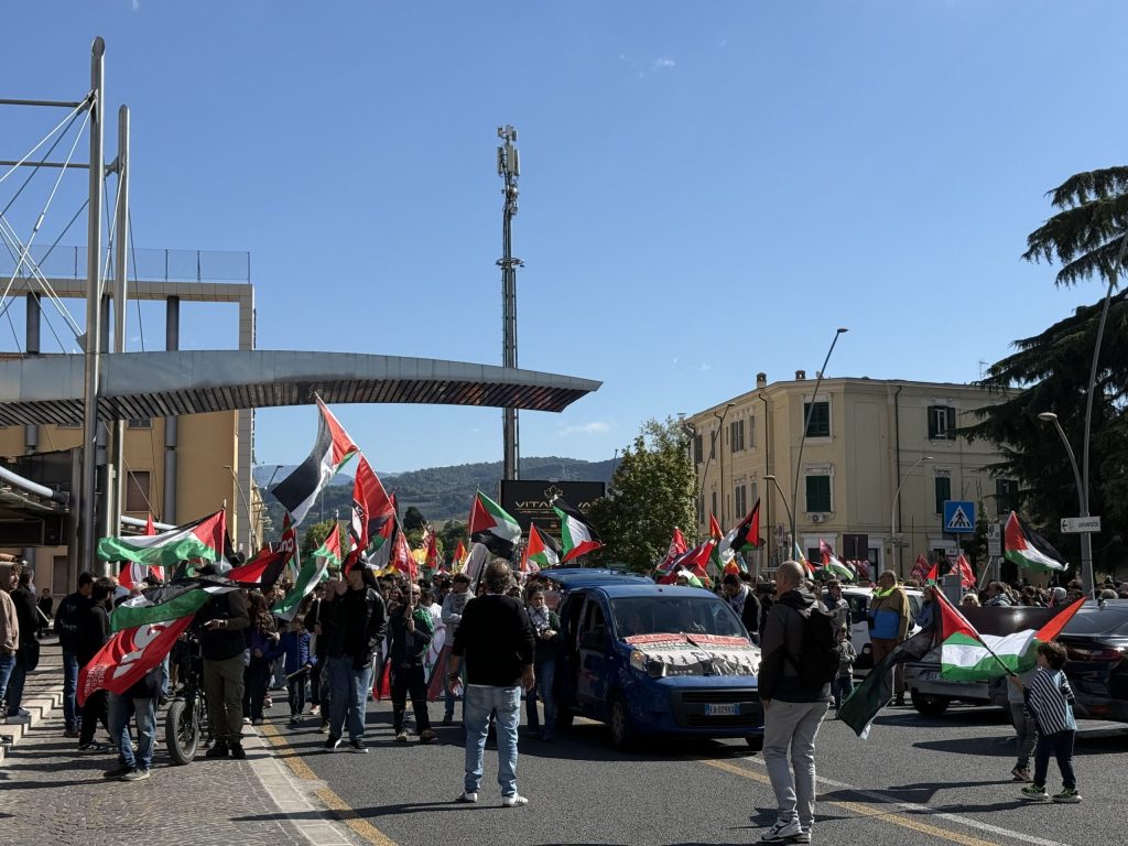 Manifestazione di protesta a Terni con persone che sventolano bandiere palestinesi e cartelli per supportare la causa palestinese.