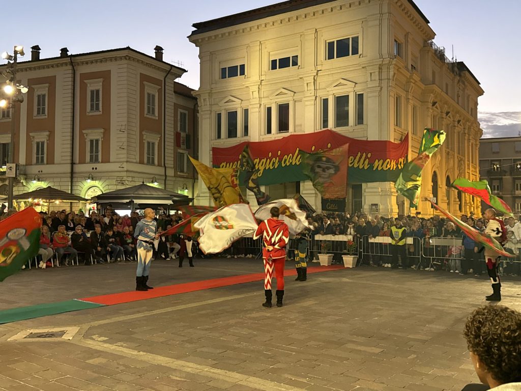 Sbandieratori in piazza della Repubblica a Terni durante la celebrazione della vittoria della Ternana, con il pubblico che assiste e diverse bandiere storiche in movimento.