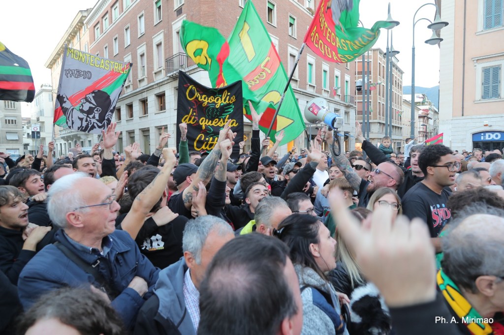 Folla festante in piazza con bandiere e striscioni, durante la celebrazione della vittoria della squadra di calcio Ternana.