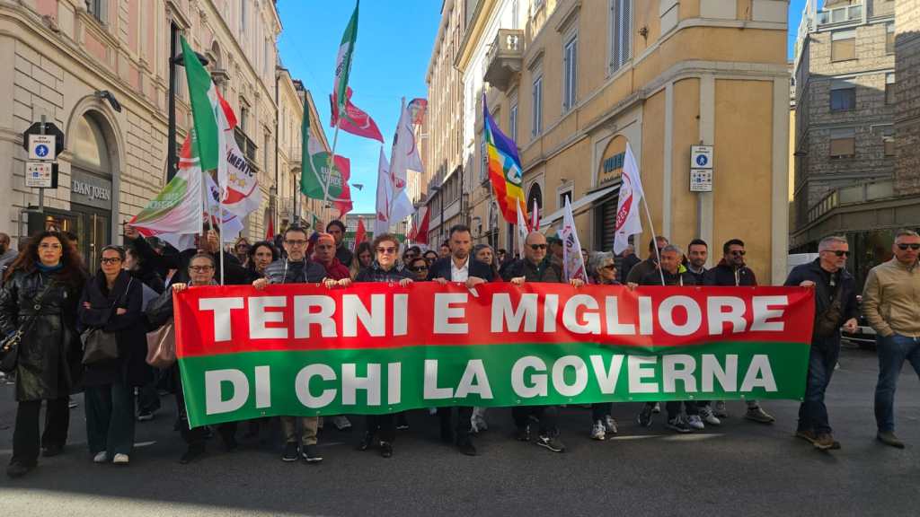Una manifestazione a Terni con un grande striscione che recita "TERNI E MIGLIORE DI CHI LA GOVERNA". La folla tiene bandiere e si muove per le vie della città.